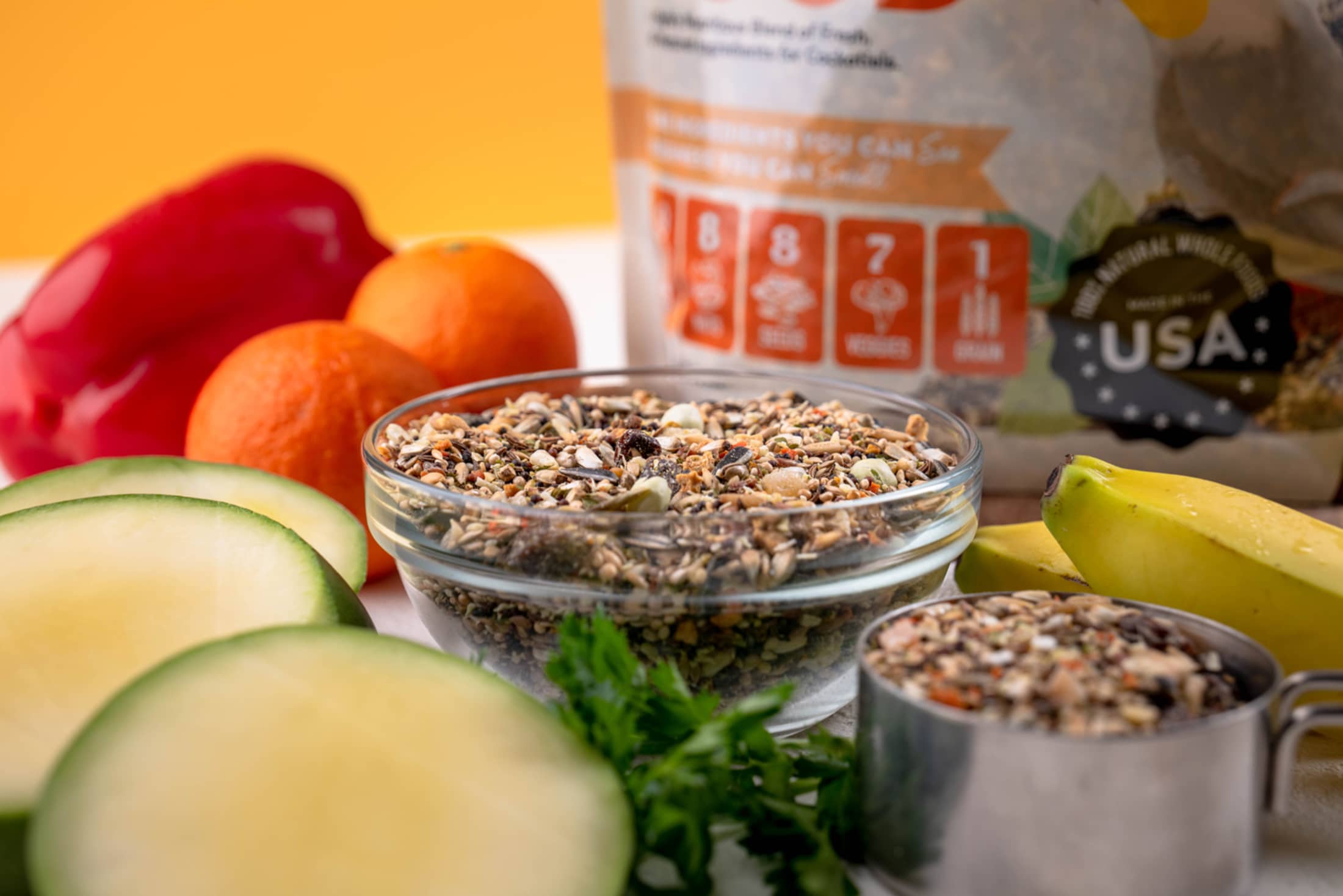 Glass bowl with granola, oranges, bananas, and a bag of Quaker oats on a table.