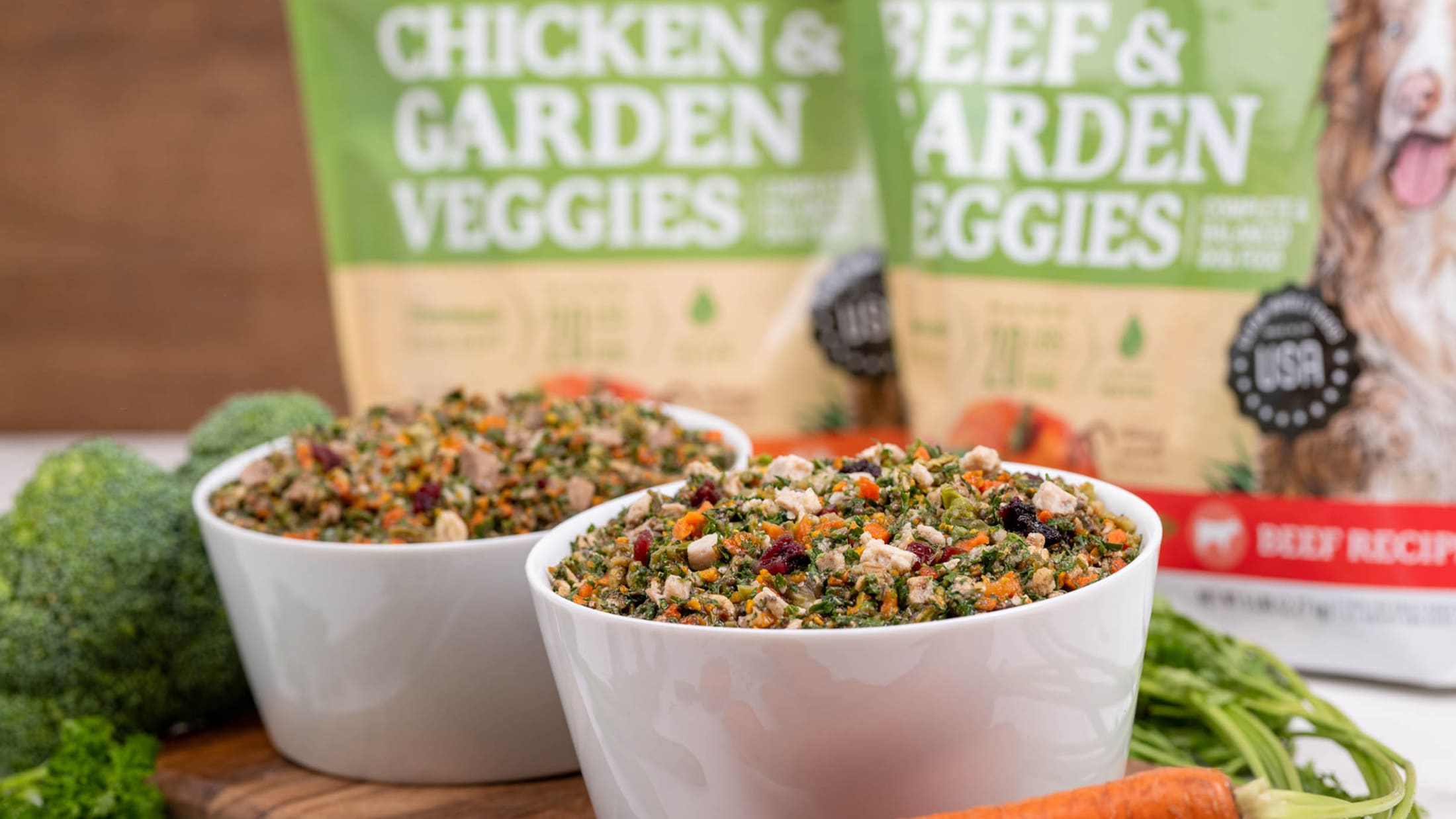 Two bowls of dog food with 'Chicken & Garden Veggies' and 'Beef & Garden Veggies' packaging in the background.